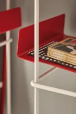 Libro Verticale prende il nome dalla particolare angolazione della mensola, leggermente inclinata indietro per far sì che i libri, cataloghi ed oggetti non cadano mai, restando sempre in posizione verticale.