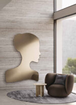 Skin Skin è uno specchio-scultura che trasforma una figura femminile in un gesto d’arredo. La sagoma delicata di un volto di donna, con i capelli raccolti in uno chignon, il lungo collo e le spalle scoperte, disegna una presenza elegante e poetica. Disponibile in un’unica dimensione e in due varianti colore, specchio naturale e bronzo, dona espressività a pareti contemporanee e angoli da personalizzare con stile.
